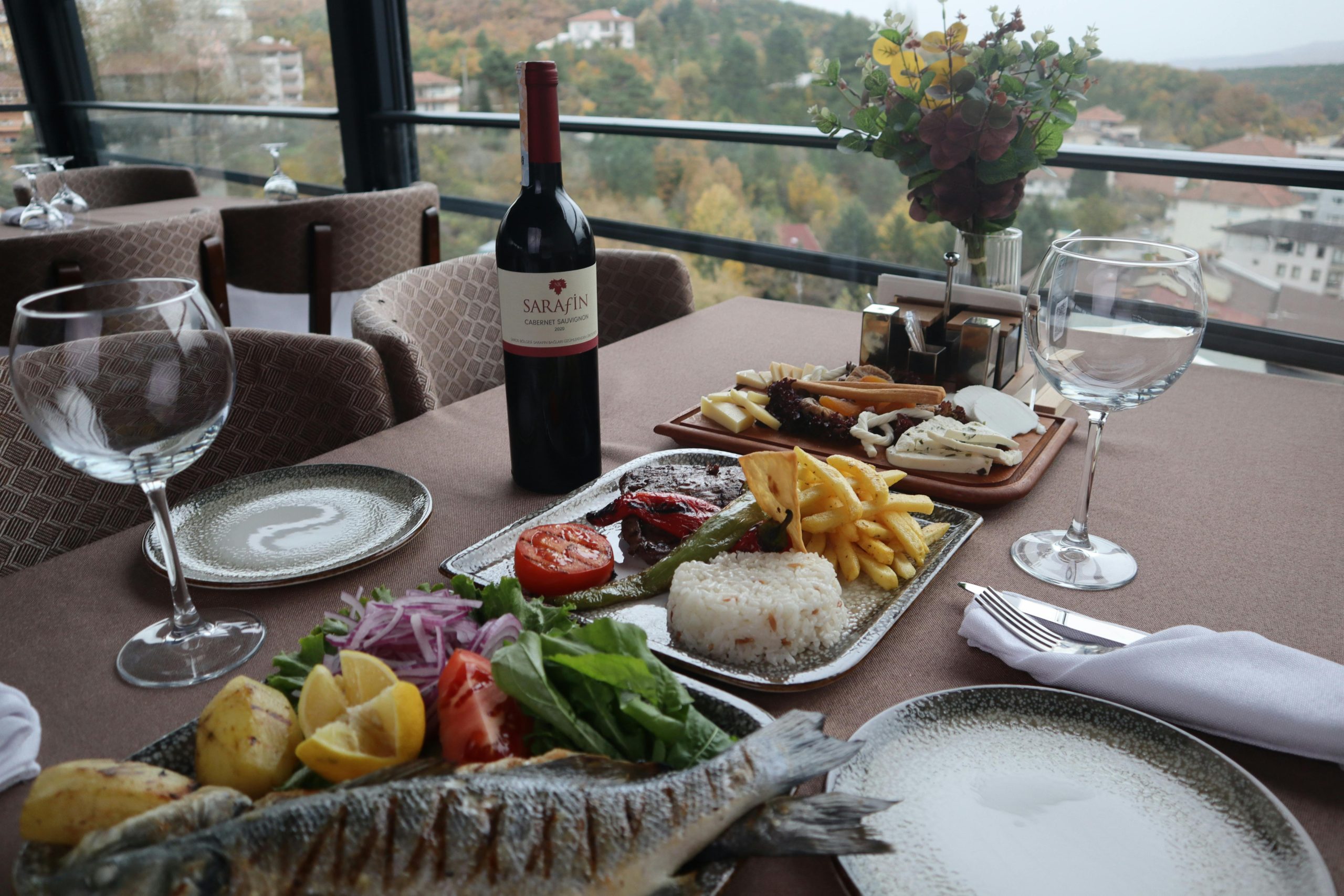 Elegantly set table with wine and gourmet dishes, offering a picturesque view of the landscape.