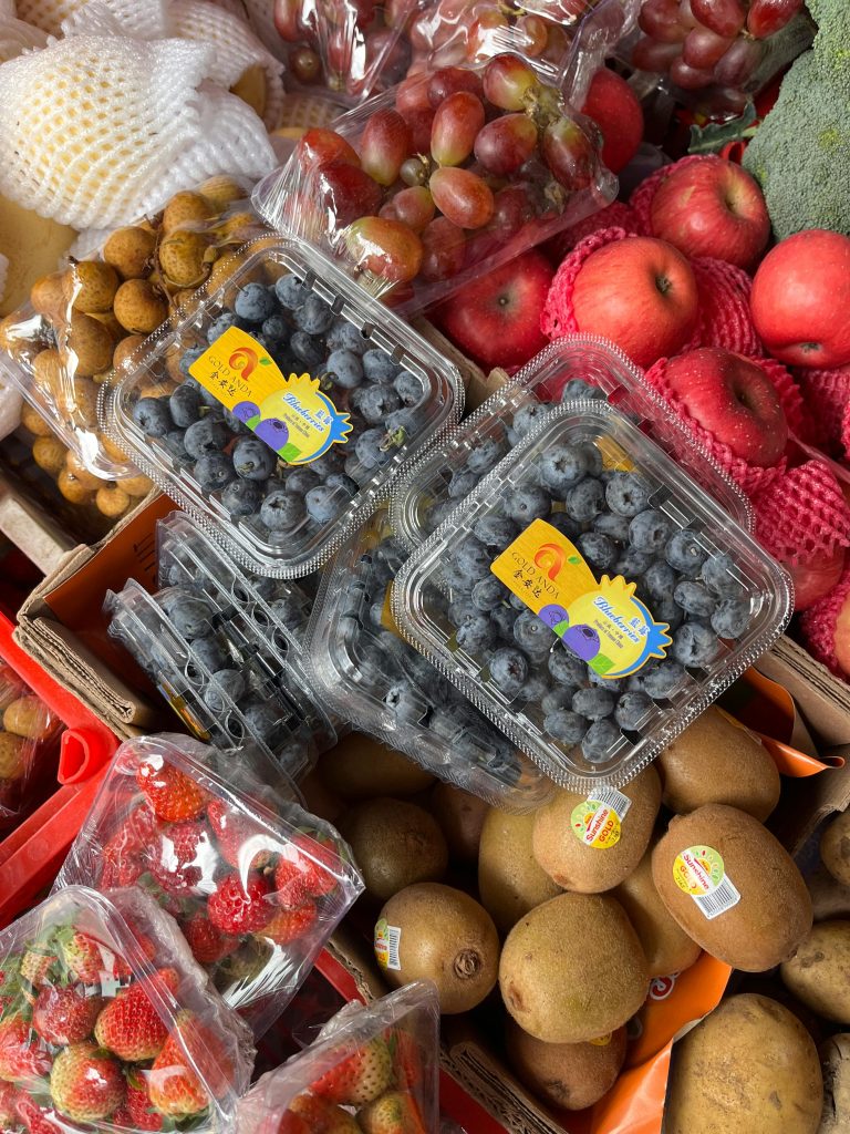 Vibrant array of fresh fruits in a market featuring blueberries, kiwis, and apples.